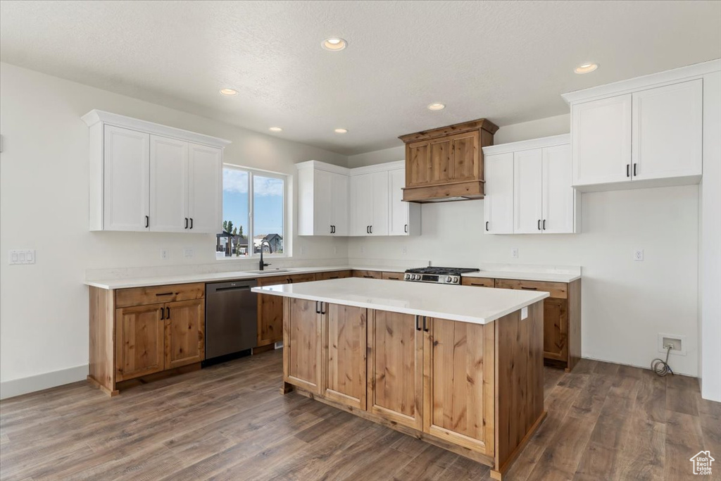 Kitchen featuring white cabinetry, stainless steel appliances, a center island, and hardwood / wood-style floors