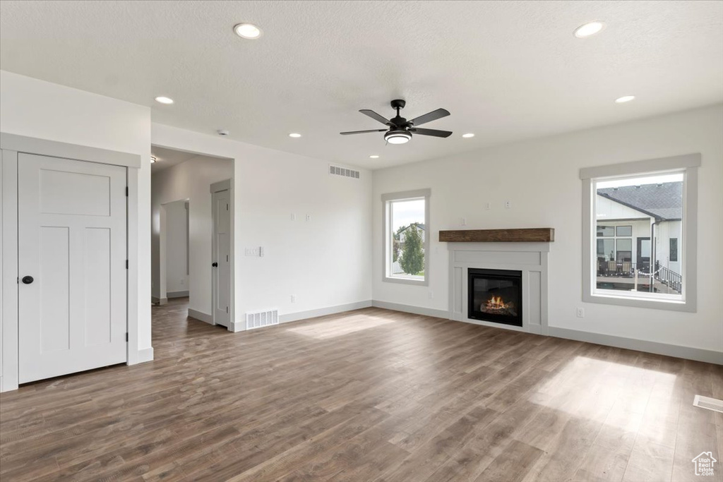 Unfurnished living room featuring ceiling fan, hardwood / wood-style flooring, and a textured ceiling