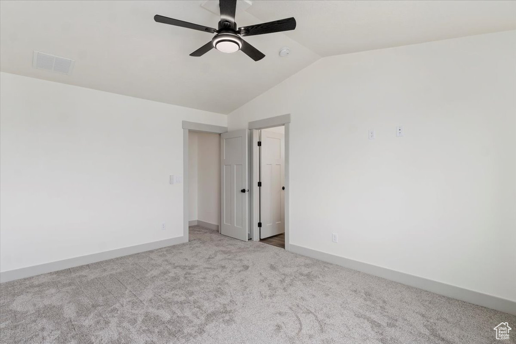 Unfurnished room featuring lofted ceiling and light carpet