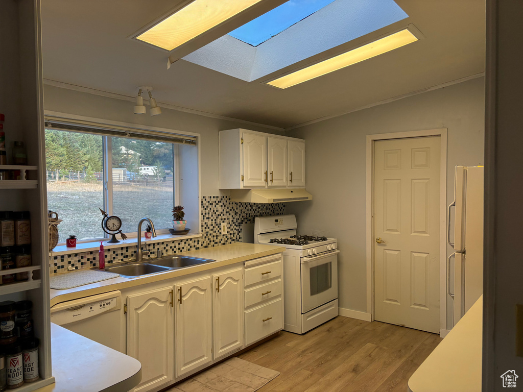 Kitchen with light hardwood / wood-style flooring, sink, crown molding, white cabinets, and white appliances