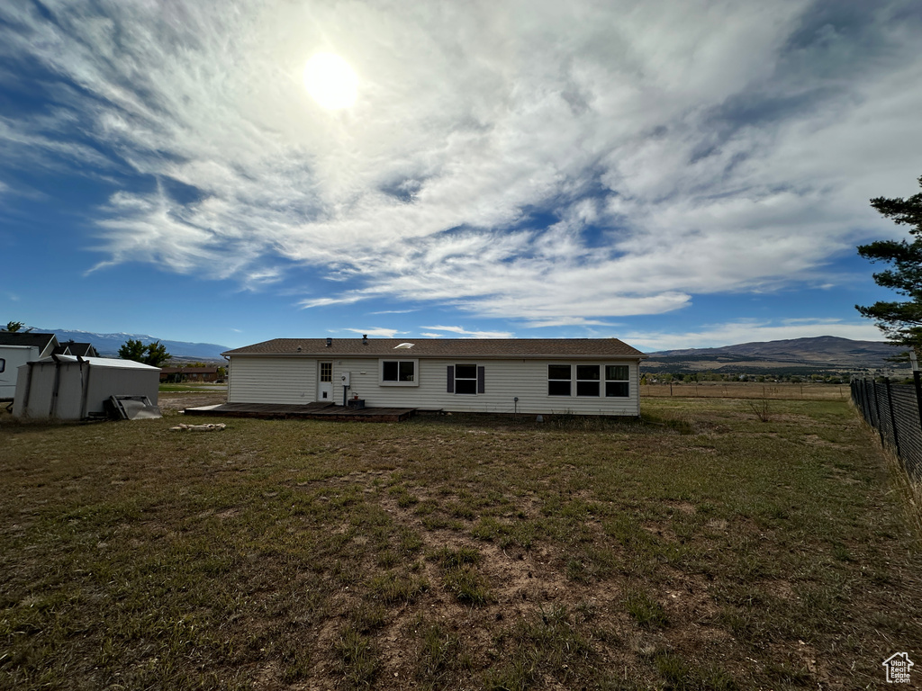 Back of property featuring a yard, a mountain view, and a storage unit