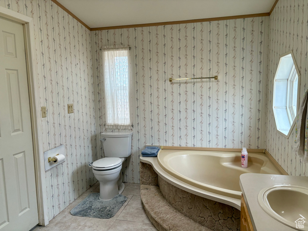 Bathroom with toilet, tile patterned flooring, a bathtub, ornamental molding, and vanity