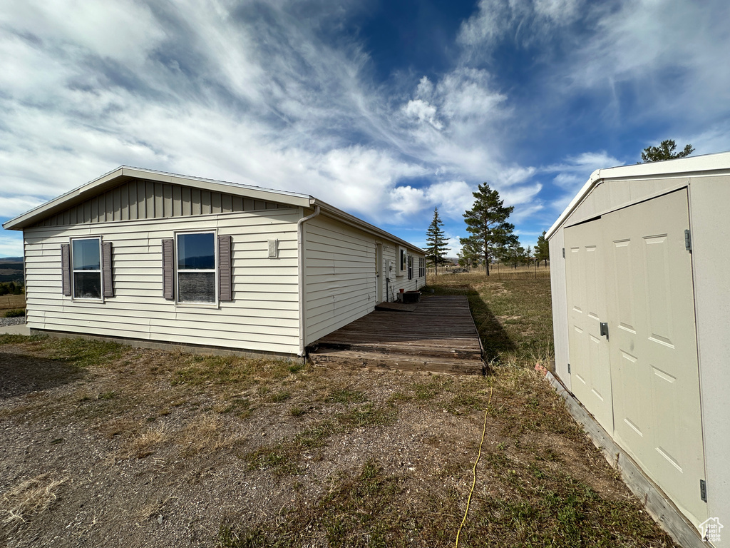 View of side of home with a storage shed and a wooden deck