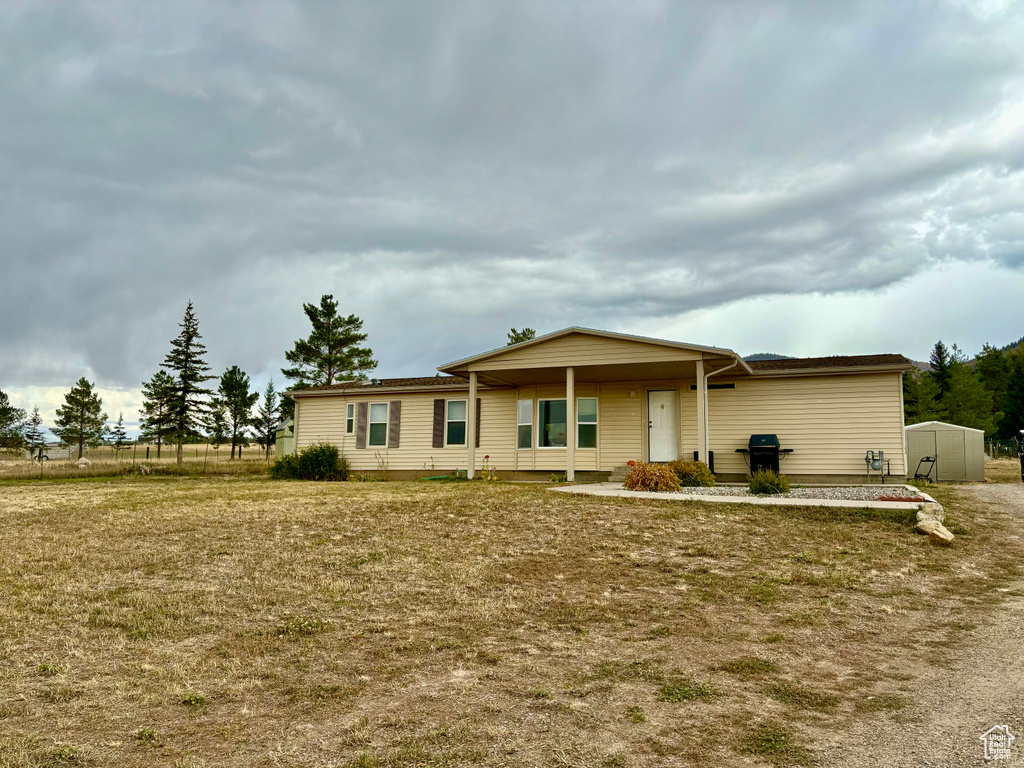 Ranch-style house with a storage unit and a front lawn