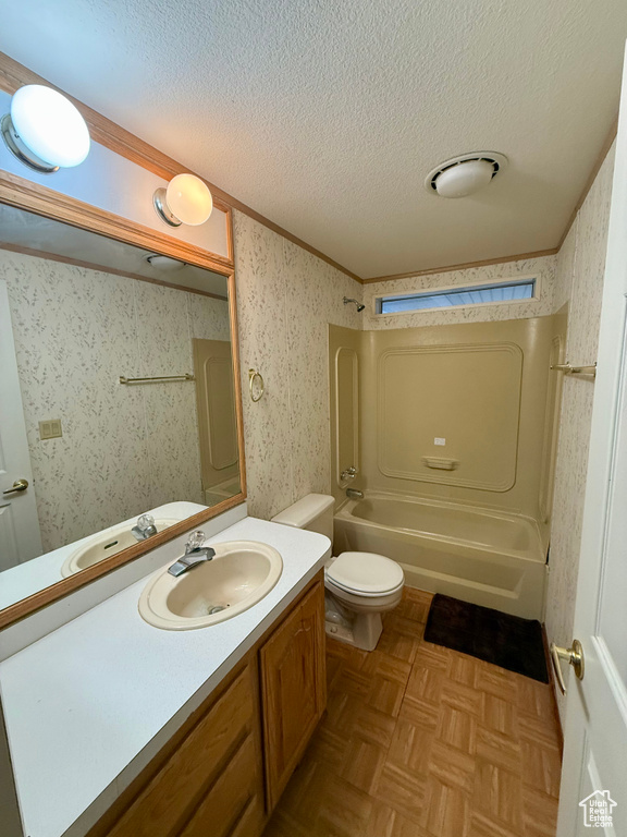 Full bathroom with shower / washtub combination, a textured ceiling, toilet, ornamental molding, and vanity