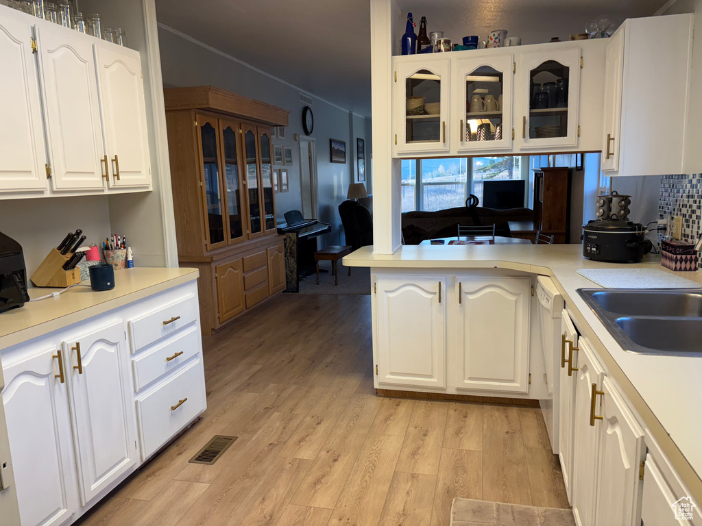 Kitchen with dishwasher, light hardwood / wood-style flooring, kitchen peninsula, sink, and white cabinetry