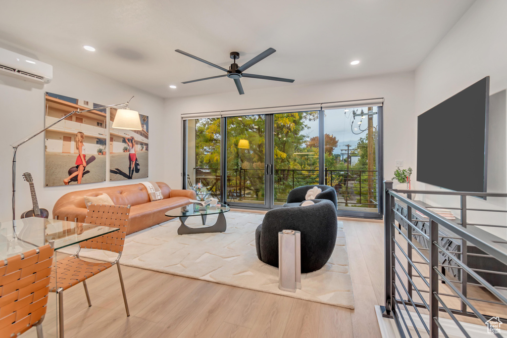 Living room featuring a wall mounted air conditioner, light wood-type flooring, and ceiling fan