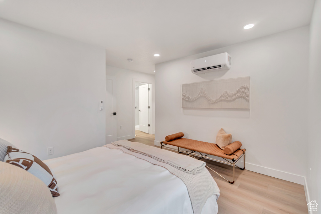 Bedroom featuring a wall mounted AC and light hardwood / wood-style floors