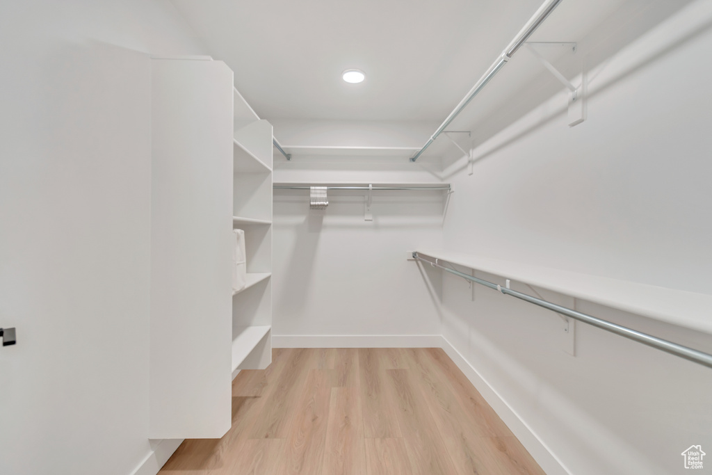 Walk in closet with light hardwood / wood-style flooring