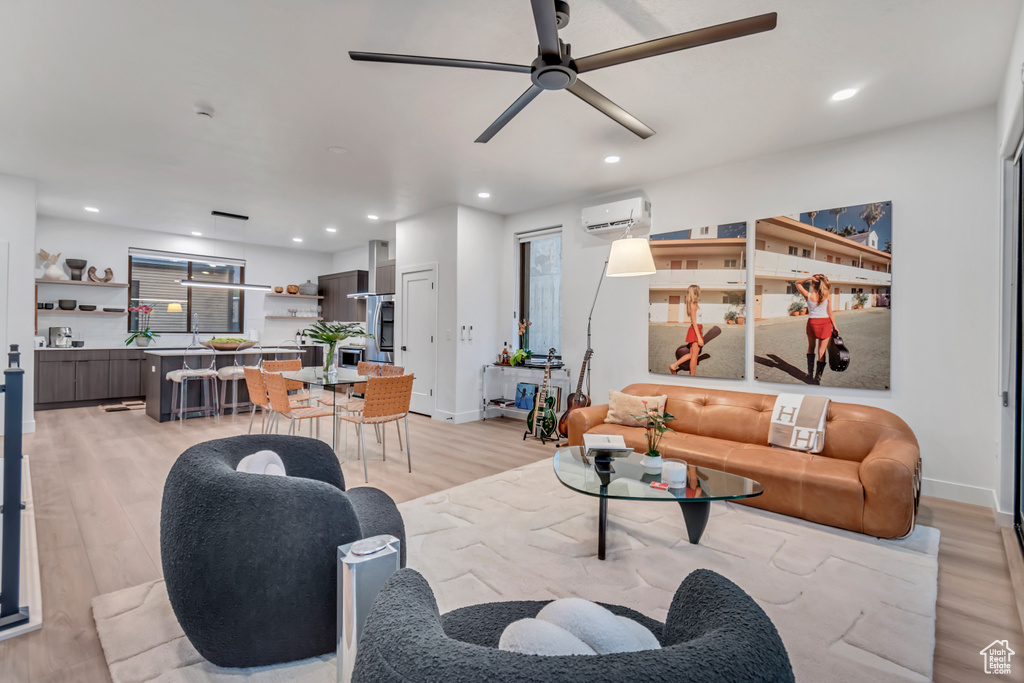 Living room featuring an AC wall unit, light wood-type flooring, and ceiling fan