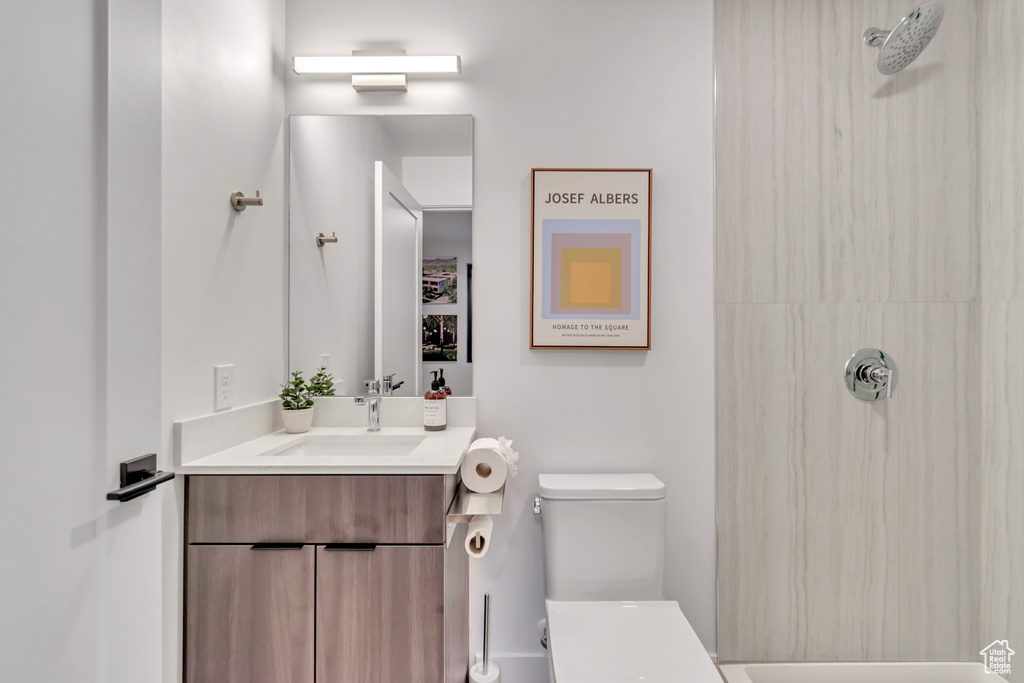 Bathroom with vanity, a tile shower, and toilet