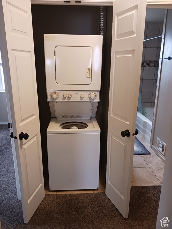 Laundry area featuring stacked washer / dryer and light colored carpet