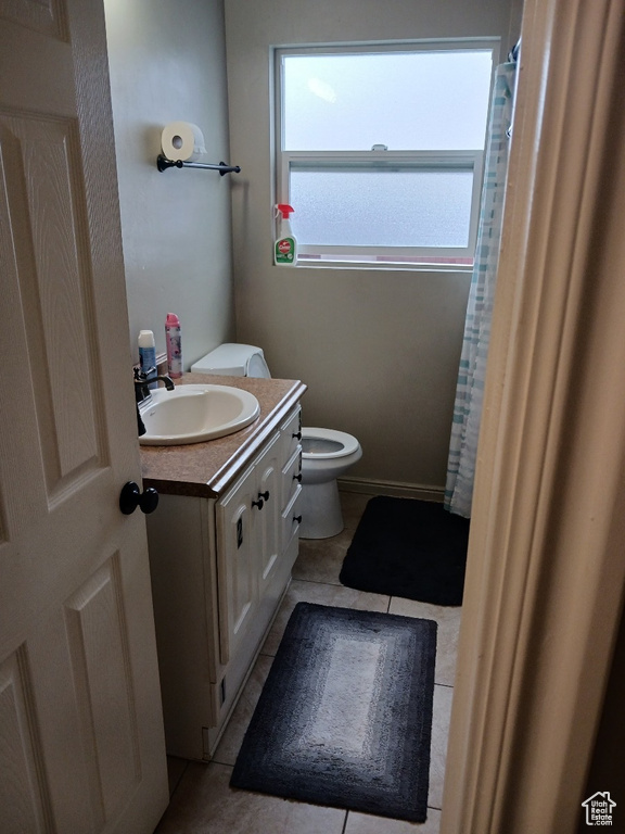 Bathroom with vanity, toilet, tile patterned flooring, and a shower with shower curtain