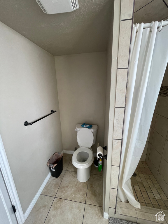 Bathroom featuring toilet, tile patterned floors, and a shower with shower curtain