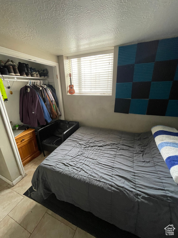 Bedroom featuring a textured ceiling, a closet, and light tile patterned floors