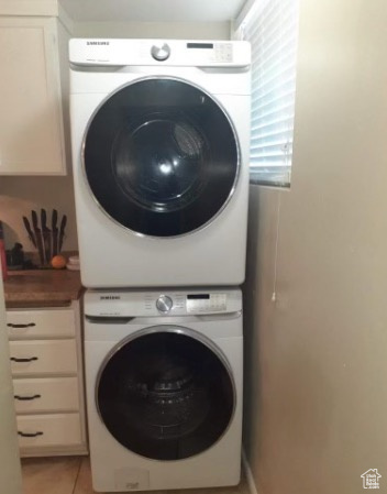 Clothes washing area with stacked washer / drying machine and light tile patterned floors