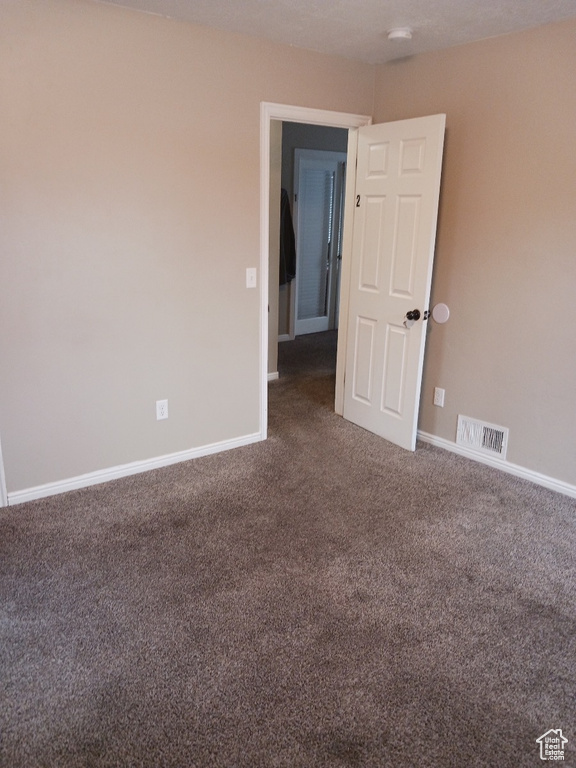 Empty room featuring dark carpet