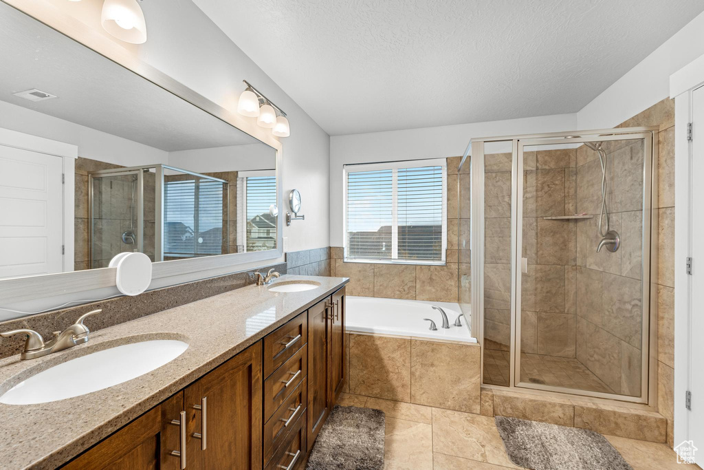 Bathroom featuring vanity, separate shower and tub, and a textured ceiling