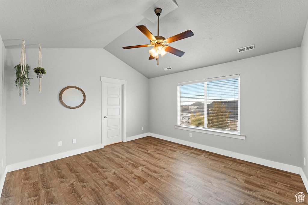 Spare room featuring ceiling fan, a textured ceiling, vaulted ceiling, and hardwood / wood-style floors