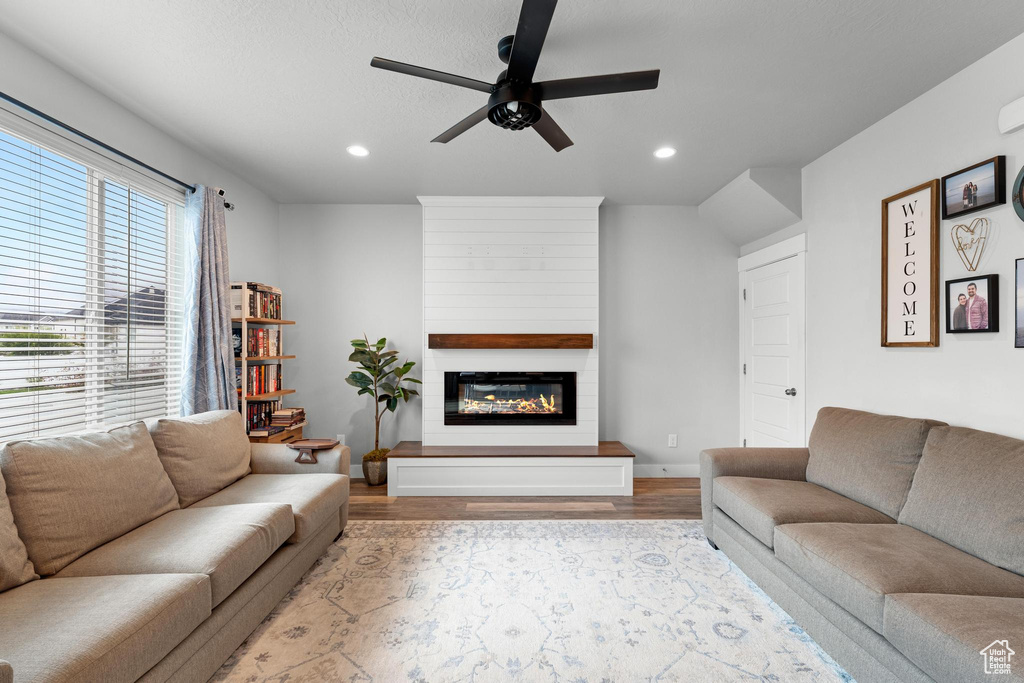 Living room featuring a fireplace, light hardwood / wood-style floors, and ceiling fan