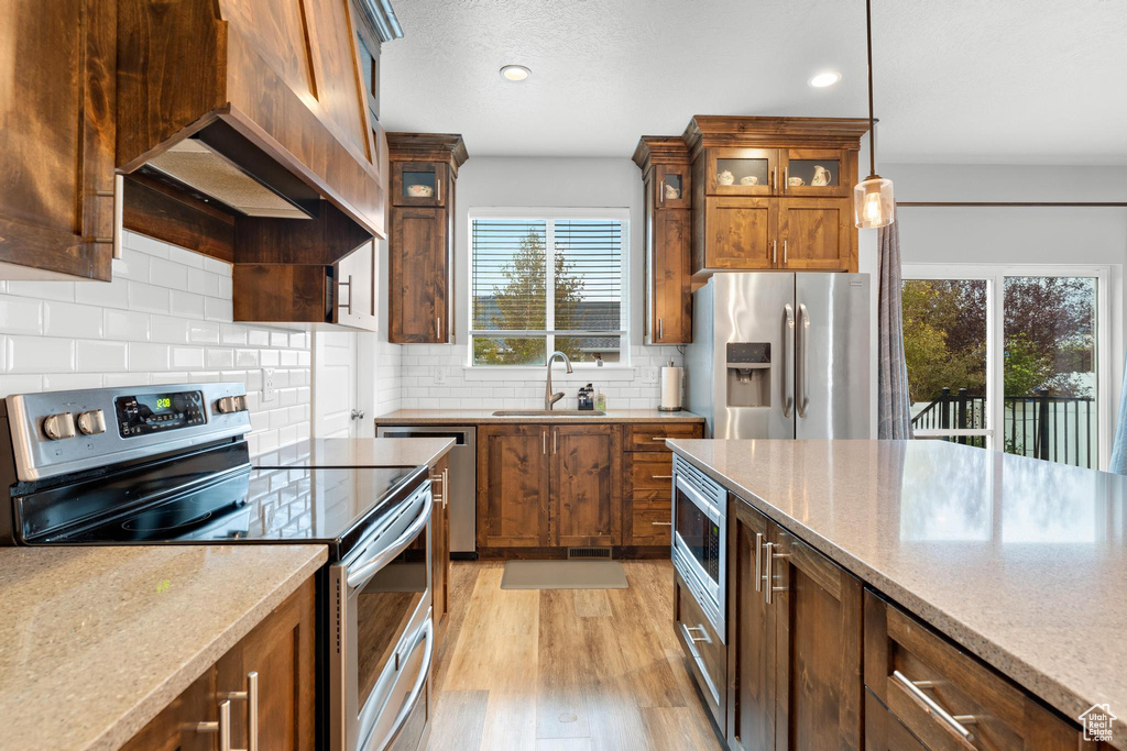 Kitchen with light stone countertops, sink, appliances with stainless steel finishes, and a healthy amount of sunlight