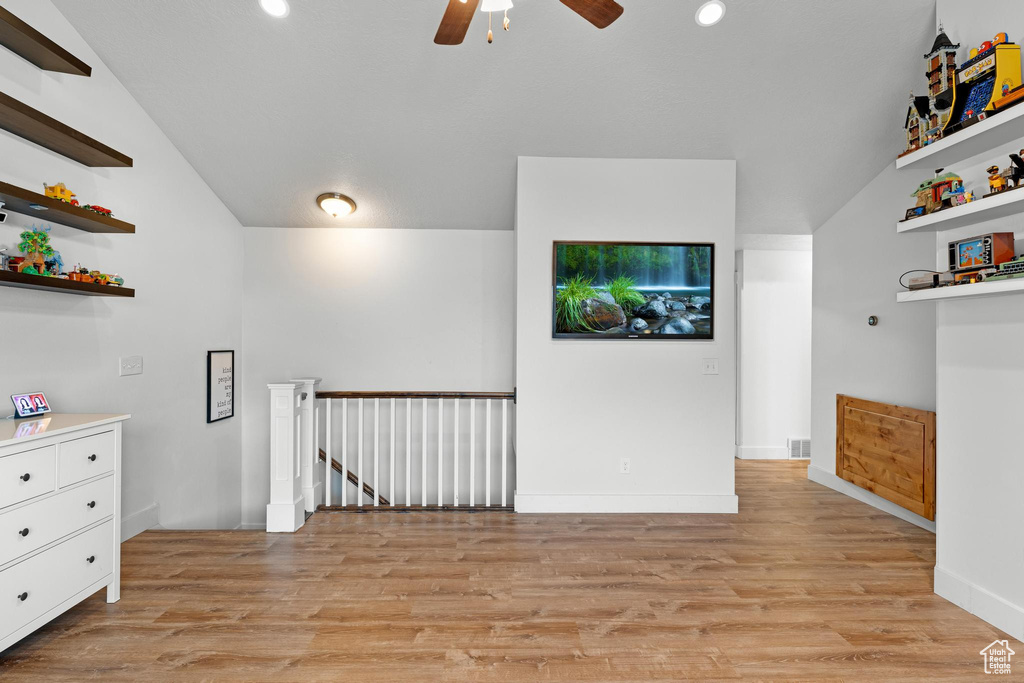 Spare room with ceiling fan, vaulted ceiling, and light wood-type flooring