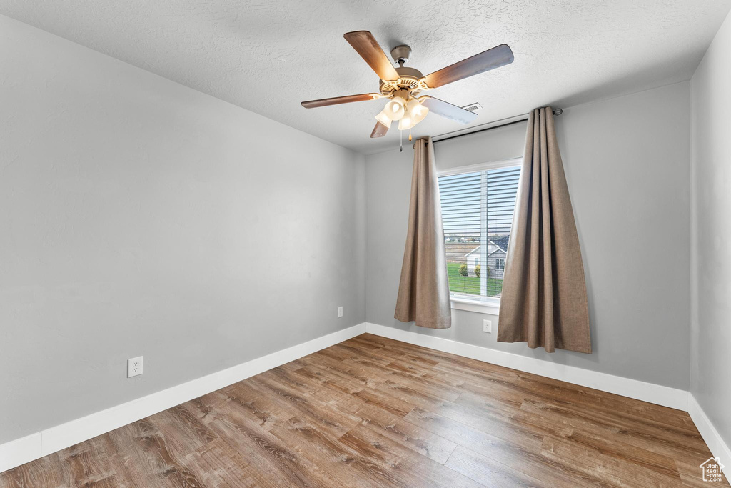 Unfurnished room with a textured ceiling, wood-type flooring, and ceiling fan