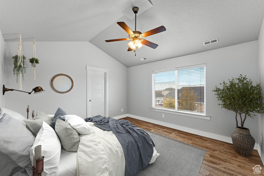 Bedroom with hardwood / wood-style floors, ceiling fan, a textured ceiling, and lofted ceiling