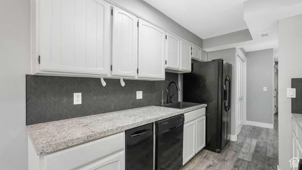 Kitchen with sink, black appliances, white cabinets, and light wood-type flooring