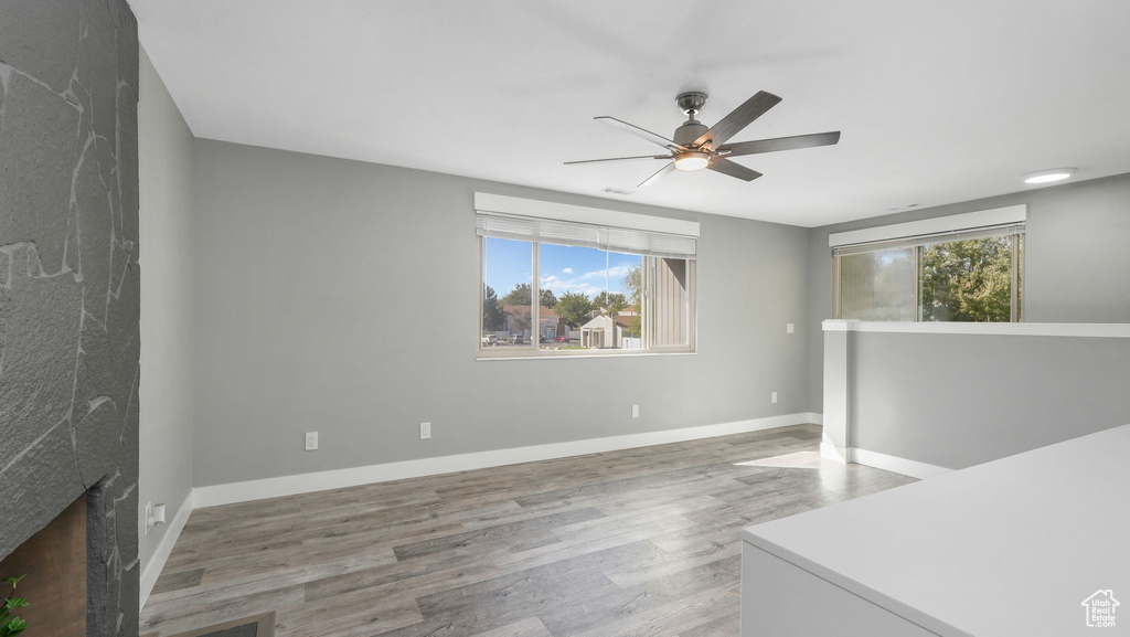 Living room featuring hardwood / wood-style floors, ceiling fan, a fireplace, and a wealth of natural light