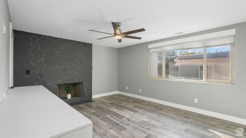 Unfurnished living room featuring a premium fireplace, hardwood / wood-style floors, and ceiling fan