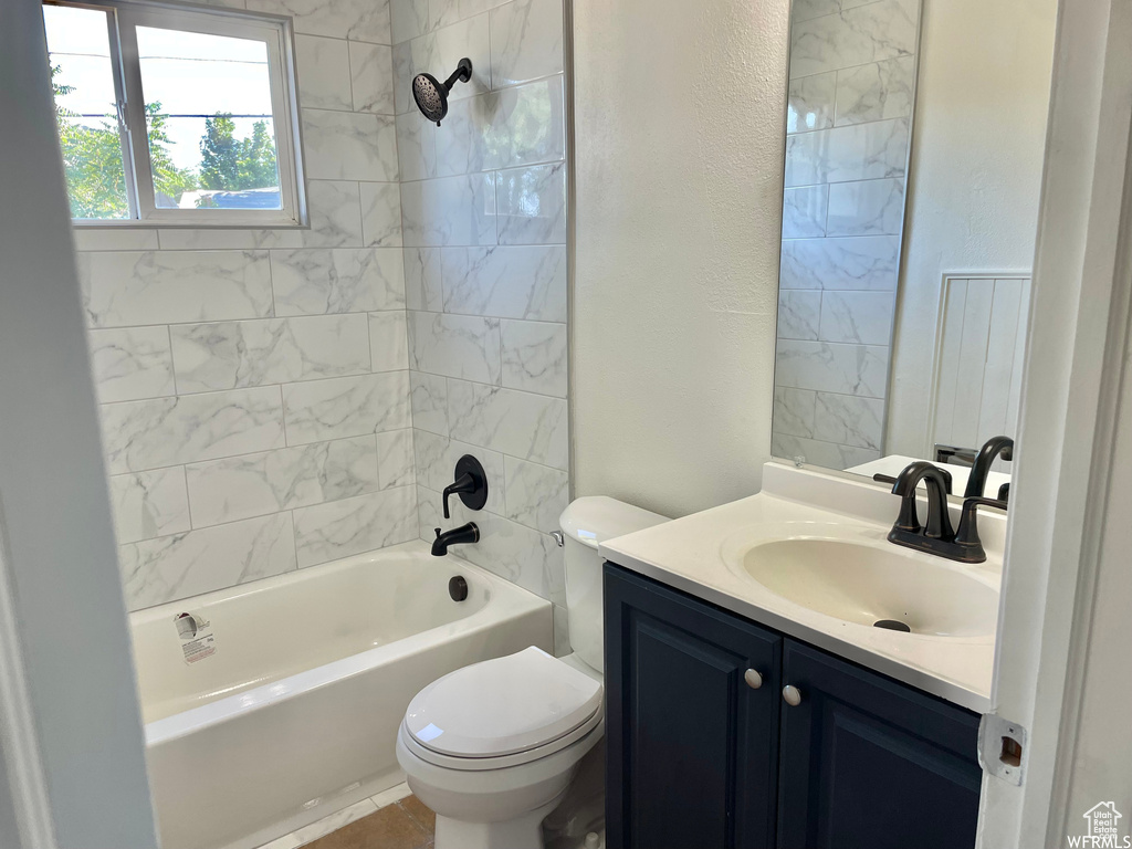 Full bathroom with vanity, tiled shower / bath combo, and toilet