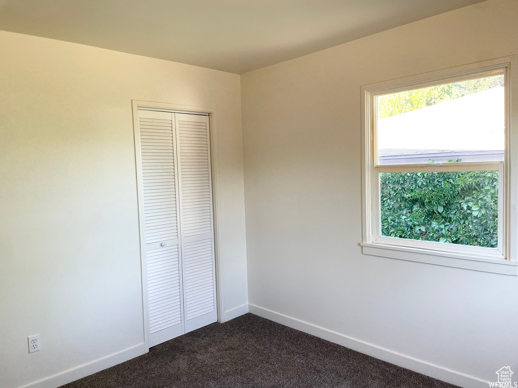 Unfurnished bedroom featuring dark carpet and a closet