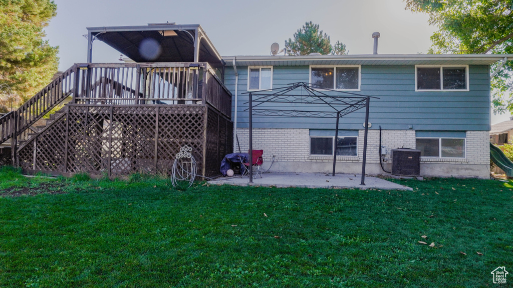 Back of property featuring a patio, a deck, a yard, and central AC unit