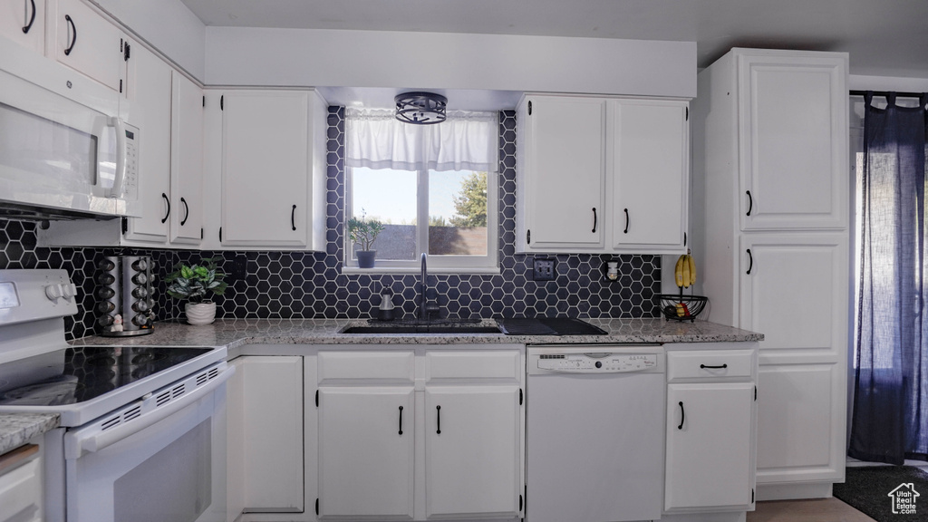 Kitchen with white appliances, white cabinetry, sink, and decorative backsplash