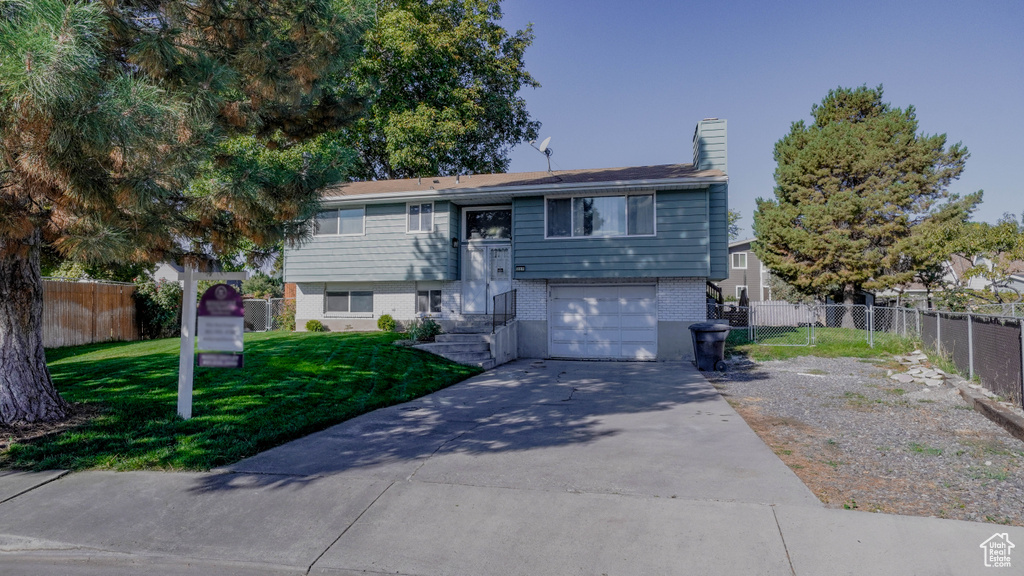 Raised ranch with a front yard and a garage