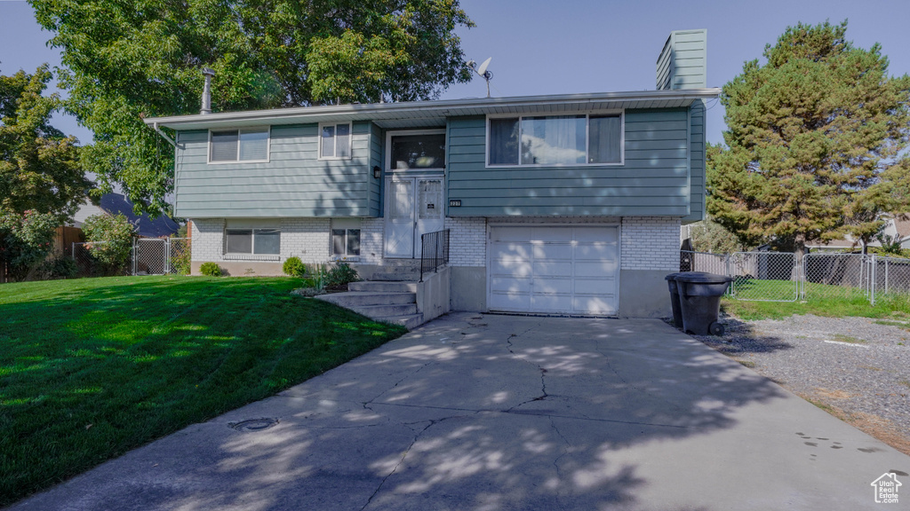 Bi-level home featuring a front lawn and a garage