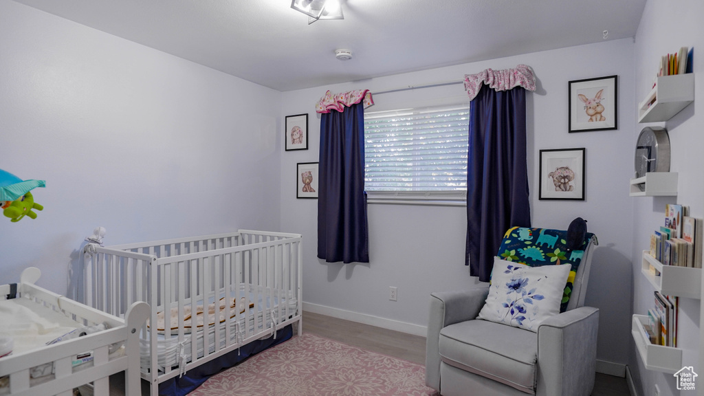 Bedroom with a nursery area and hardwood / wood-style flooring