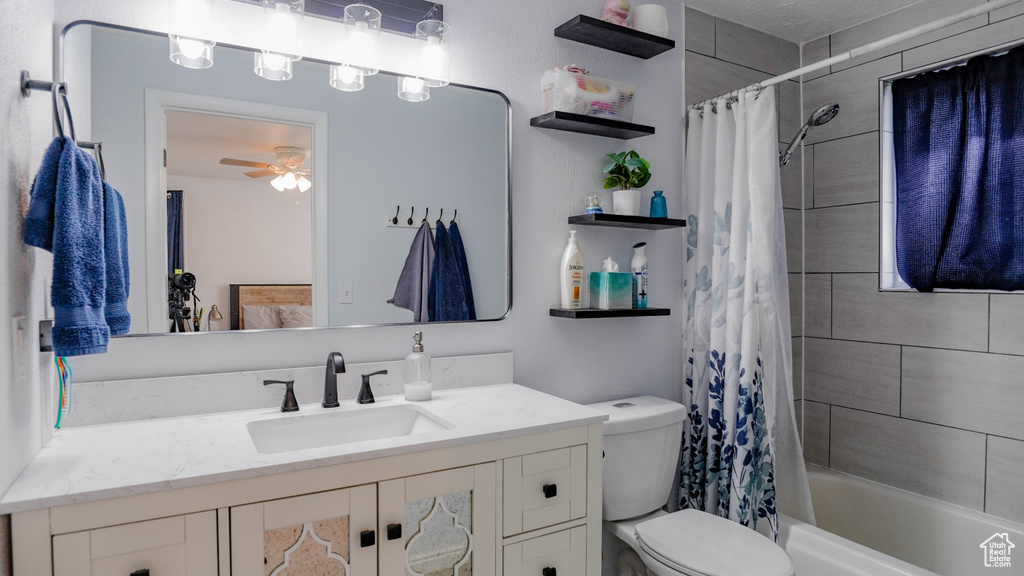 Full bathroom with vanity, shower / bath combo with shower curtain, toilet, and ceiling fan