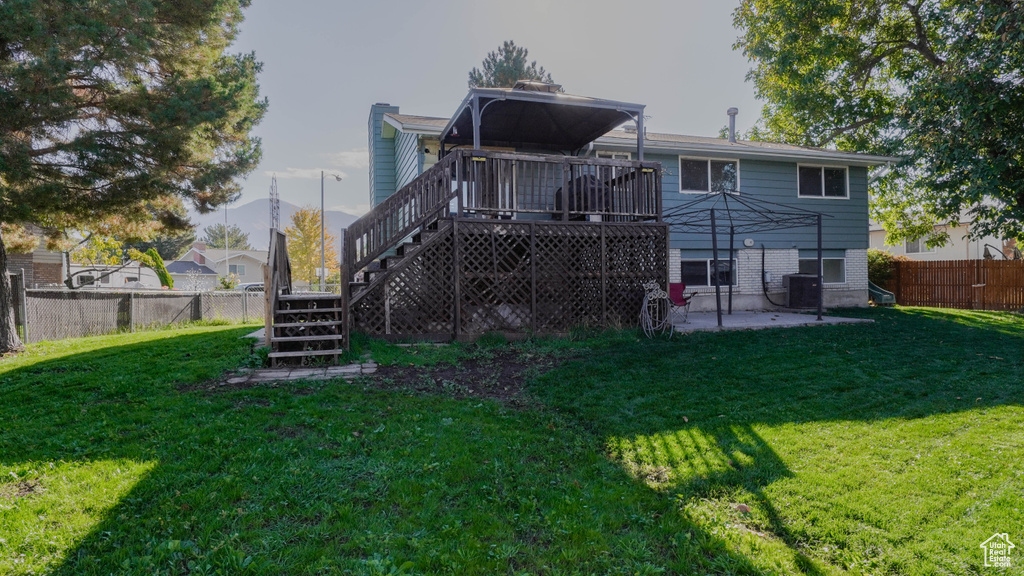 Back of property with a deck, a patio, and a lawn