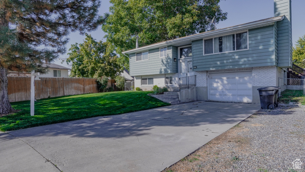 Split foyer home featuring a front yard and a garage