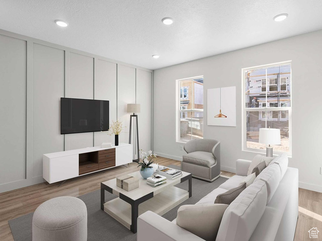 Living room with a textured ceiling, wood-type flooring, and plenty of natural light