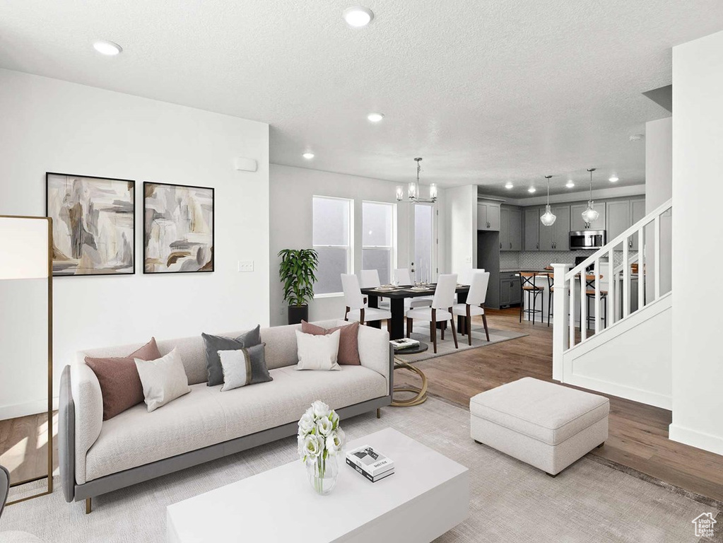 Living room with a textured ceiling, an inviting chandelier, and hardwood / wood-style floors