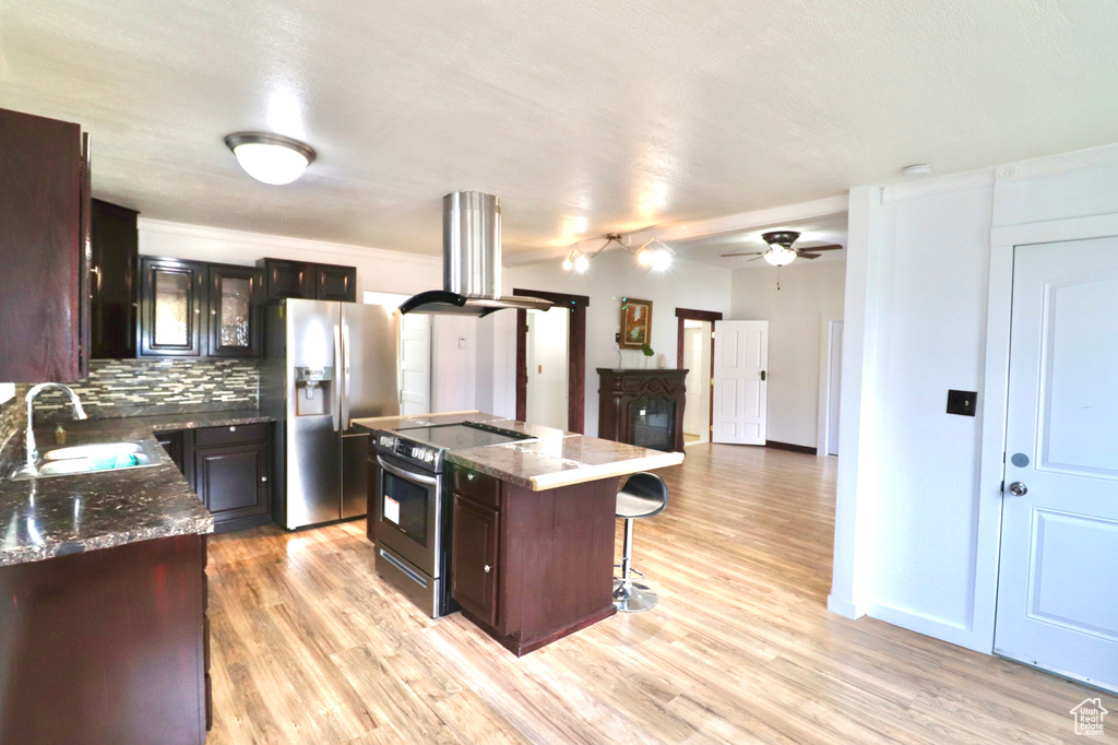 Kitchen featuring appliances with stainless steel finishes, sink, light wood-type flooring, a kitchen island, and island exhaust hood