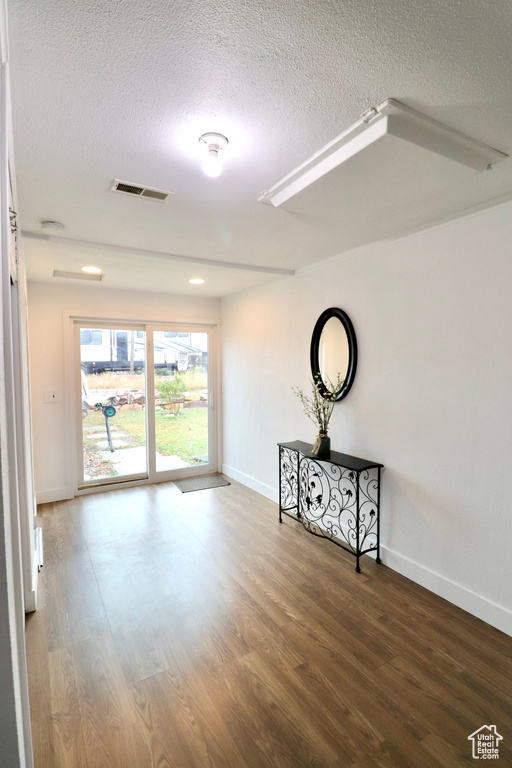 Empty room with a textured ceiling and hardwood / wood-style flooring