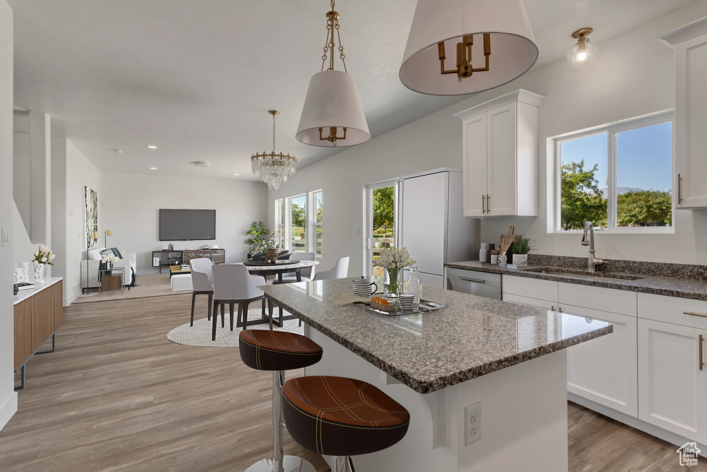 Kitchen with white cabinetry, light wood-type flooring, dishwasher, pendant lighting, and sink