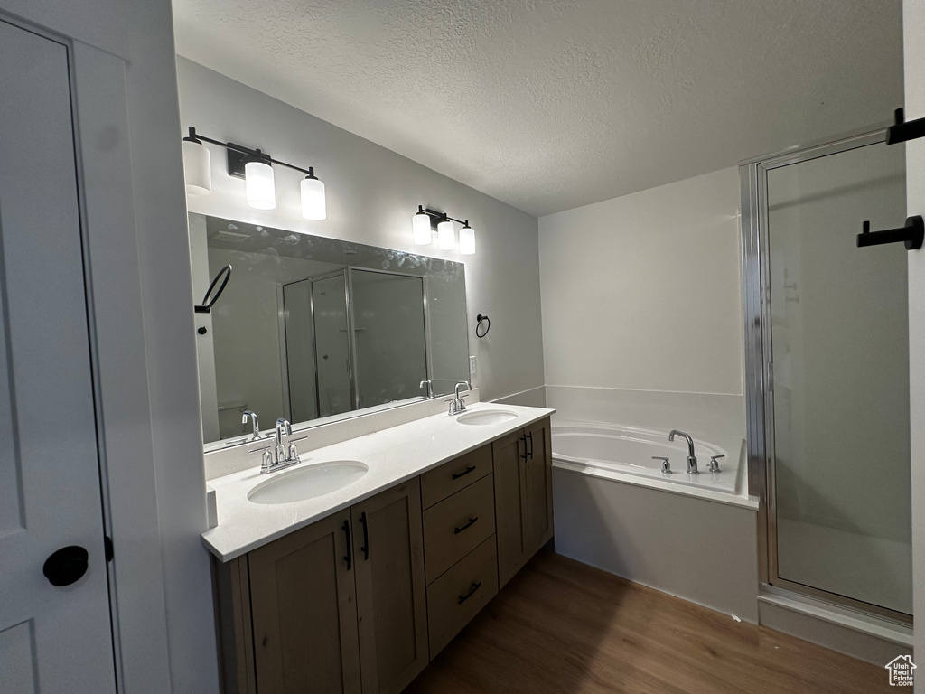 Bathroom with vanity, a textured ceiling, shower with separate bathtub, and hardwood / wood-style floors