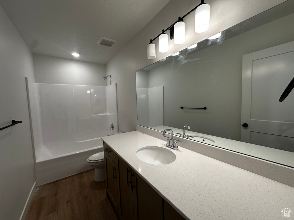 Full bathroom with vanity, hardwood / wood-style floors, shower / tub combination, and toilet