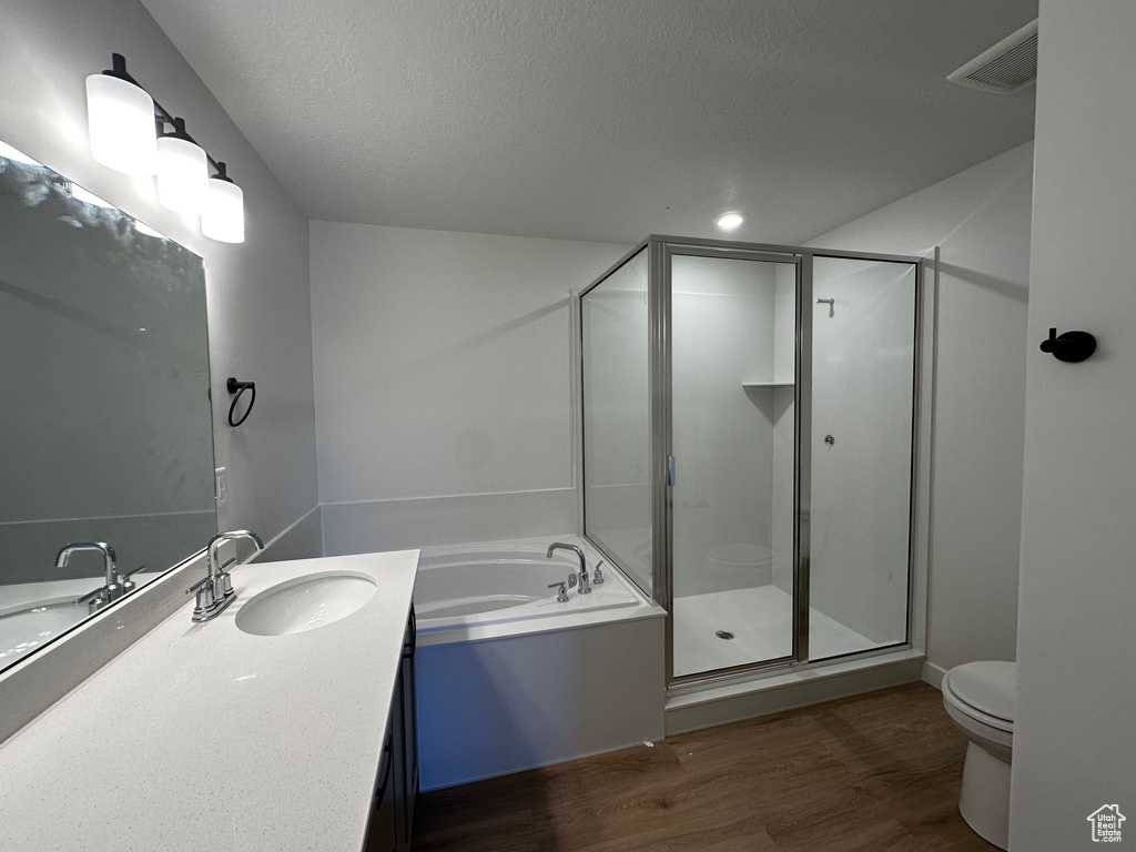 Full bathroom featuring a textured ceiling, separate shower and tub, toilet, vanity, and hardwood / wood-style flooring