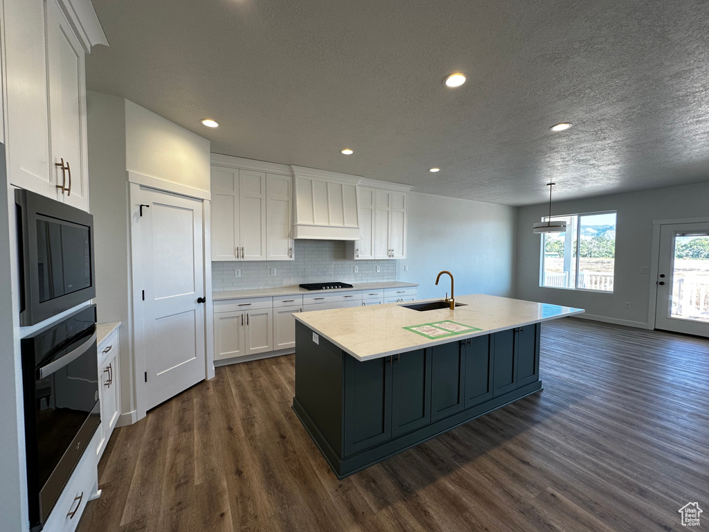 Kitchen featuring stainless steel oven, dark wood-type flooring, sink, custom exhaust hood, and white cabinets